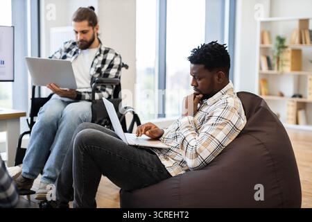 Two professionals collaborating in casual workspace with laptops Stock Photo