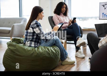 Team members collaborating using digital devices in modern workspace Stock Photo