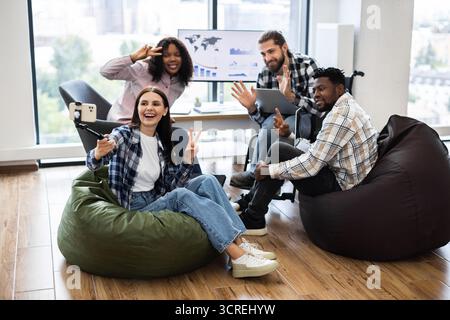 Diverse group of coworkers taking selfie during casual office meeting Stock Photo