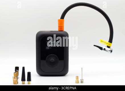 Compact portable black air compressor with a digital display and various inflation adapters. Stock Photo