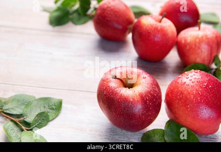 Fresh red gala apples with green leaves and water drops on rustic wooden surface Stock Photo