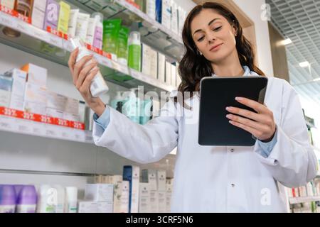 Woman in uniform holding clipboard checking medicine supplies Stock Photo