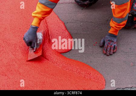 Application of red road surfacing on a cycle lane, inner-city road, so-called cold plastic surfacing, in the colour traffic red, RAL3020, the coloured Stock Photo