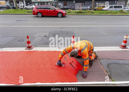 Application of red road surfacing on a cycle lane, inner-city road, so-called cold plastic surfacing, in the colour traffic red, RAL3020, the coloured Stock Photo