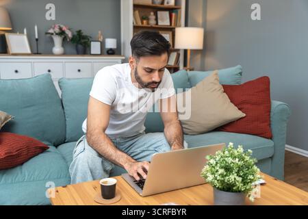 Young university student, freelancer business man, working at home on laptop computer, testing new innovative technology and online internet tools whi Stock Photo