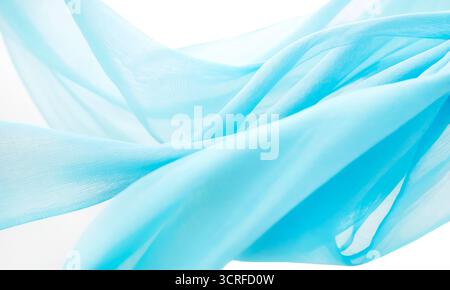 Transparent light blue fabric draped in waves on white background Stock Photo