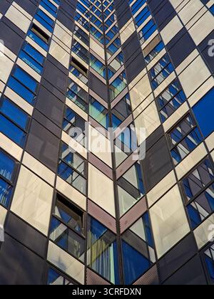 abstract view of a modern skyscraper facade featuring a repeating checkerboard pattern of dark panels and reflective windows in shades of blue and whi Stock Photo