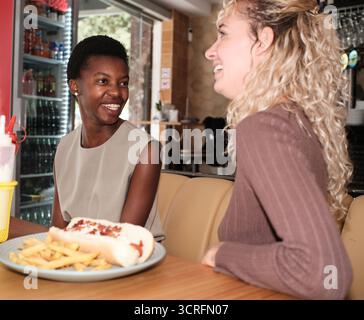 Diverse women friends enjoying lunch hot dogs Stock Photo