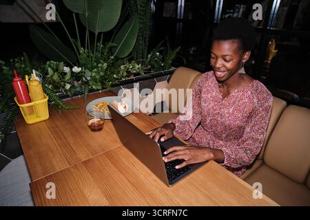 Woman remote working at restaurant with laptop Stock Photo