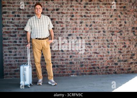 Portrait of happy senior man with his luggage. He is looking at camera and smiling. Senior people traveling. Stock Photo