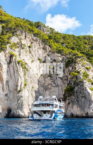 day trip tourist pleasure cruise boat off the coast of the Greek Ionian Island of Zante or Zakynthos with cliffs behind. Stock Photo