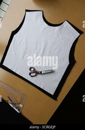 Detail of a cut pattern on black fabric on a tailor's table. Professional scissors ready for cutting. Concepts of sewing, tailoring, craftsmanship Stock Photo