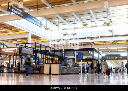 Passengers at Kansas City International Airport (MCI or KCI) in Kansas City, Missouri, walk through the concourse under "Ornithology" by Willie Cole Stock Photo