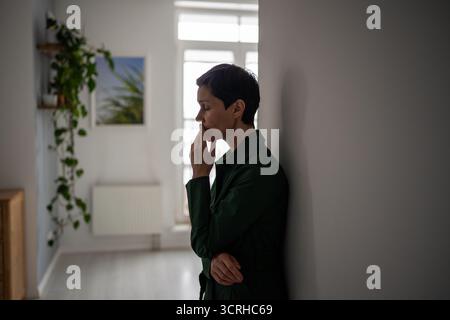 Tired hopeless mature woman leaning on wall in mental struggle and deep personal crisis alone Stock Photo