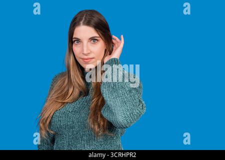 Young adult woman looking at camera, hand gently touching long hair Stock Photo