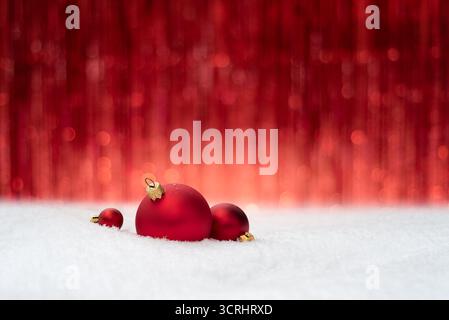 Christmas Background With Red Baubles On Snow Against Festive Red Backdrop With Copy Space For Design Stock Photo