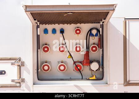 Industrial electrical control panel on a truck trailer with red round connectors and cables in the open door Stock Photo