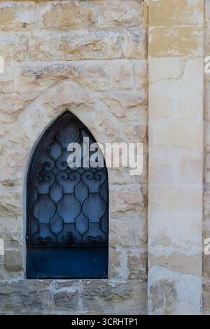 Rustic Stone Wall With Arched Window And Decorative Iron Bars On Exterior Building Stock Photo
