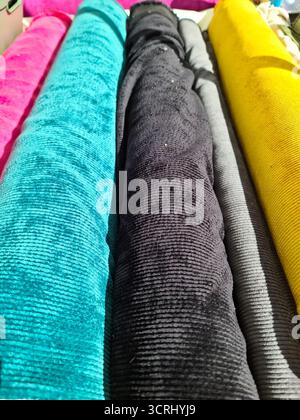 Rolls of vibrant corduroy fabric, including pink, blue, black, gray, and yellow, showing rich texture for textiles and crafts Stock Photo