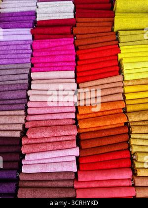 Colorful fabric swatches showcasing a variety of textures and patterns, neatly arranged in rows by color gradients Stock Photo