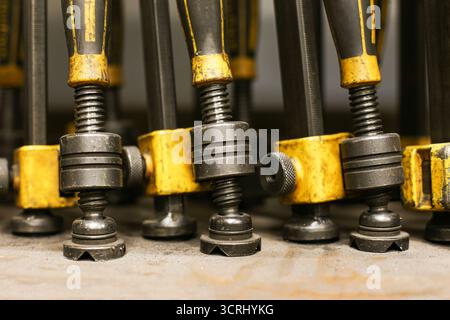 Welding clamps in workshop. Industrial metal tools closeup. Heavy duty construction equipment background. Mechanical engineering objects for work. Stock Photo