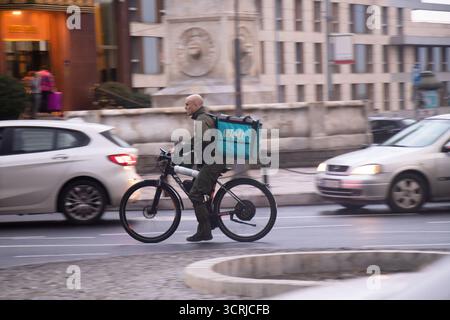 Belgrade, Serbia - October 1, 2025: Young bold man riding an electric delivery bike for Wolt service on busy city street in the evening Stock Photo