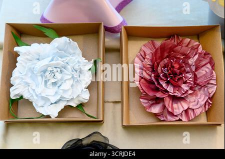 A set of handmade flower-shaped brooches or pins.Close-up of textile flowers: white rose and burgundy fabric peony in gift boxes. Stock Photo