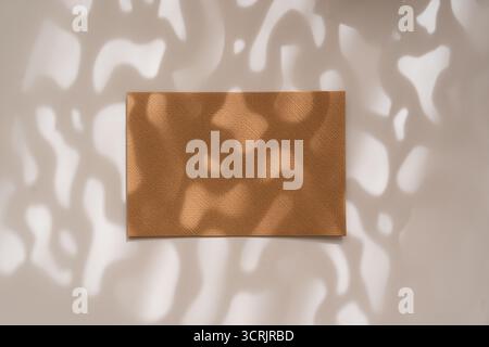 Brown-orange empty kraft sheet with artistic shadows on white background, flat lay. Invitation or greeting card mock up Stock Photo