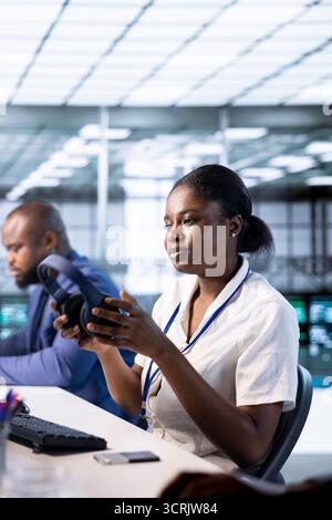 Woman in data center putting headphones on while using programming languages to construct applications. Server hub employee listening podcasts to make time pass faster while debugging code Stock Photo