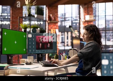 Focused woman using AI chatbot software and copy space display, turning text prompt into photos for a creative project. Young photographer uses text to image generative models on PC. Stock Photo