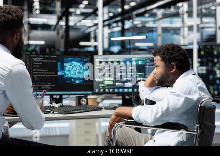 Data center supervisor and programmer with paraplegia using artificial intelligence computerized model. Server room manager and IT expert with disability using machine learning AI algorithms Stock Photo