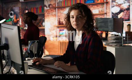 Portrait of happy woman working in AI tech agency providing custom software development services. Jolly IT staff member using machine learning to streamline coding process in startup office, camera A Stock Photo