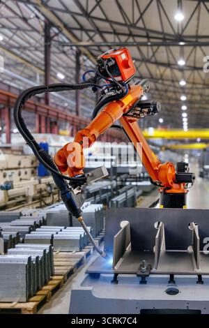 Industrial robot is welding metal part. Stock Photo