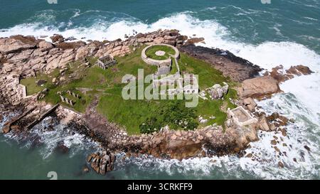 Aerial view of an old abandoned fortress in ruins from the 18th century on an isolated island full of rocks and vegetation surrounded by the sea Stock Photo