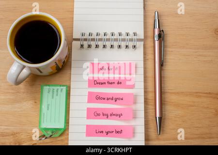 Bright sticky notes with English text on a notebook, alongside a pen, tag and coffee mug on a wooden desk—perfect for themes of planning, journaling, Stock Photo