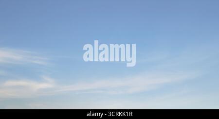 Clean soft pale blue sky with very faint almost imperceptible wisps cirrus clouds. Sky smooth gradient shifting from slightly lighter shade bottom pas Stock Photo
