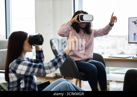 Women using virtual reality glasses in modern workspace environment Stock Photo
