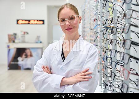 Optician woman standing in optical shop with eyeglasses Stock Photo