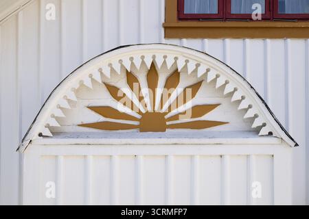 Detail of an ornament symbolising the sun in yellow and white on a wooden house, Fjaellbacka, Bohuslaen, western Sweden, Sweden Stock Photo