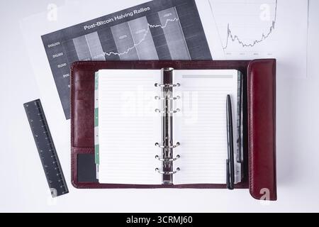 A notebook with a pen lies on financial charts Stock Photo