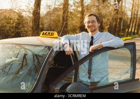 Portrait of smiling caucasian taxi driver near car, looking at camera. Stock Photo