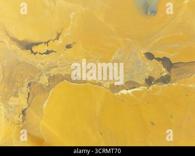 Aerial view of swirling ochre and umber earth tones blend in a surreal landscape, creating a painterly canvas of textures and hues, Minas de Ríotinto, Stock Photo