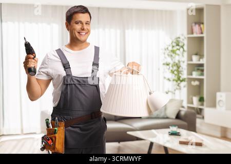 Worker holding a lampshade and a power screwdriver in a living room Stock Photo