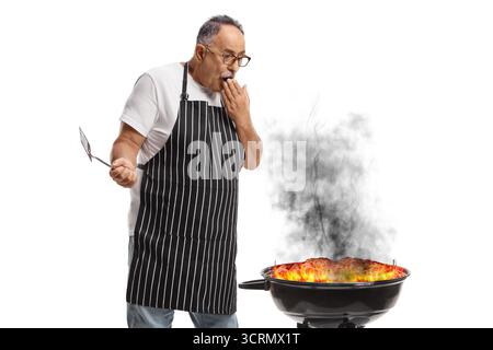 Man standing next to a burning bbq isolated on white background Stock Photo