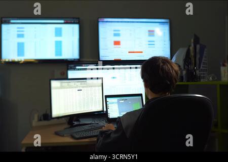 The hacker sits behind the monitor and works. The work of computer technician and programmer. Stock Photo