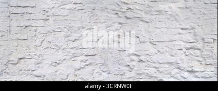 Rough, uneven, white painted stone wall, dirty and with splashes Stock Photo