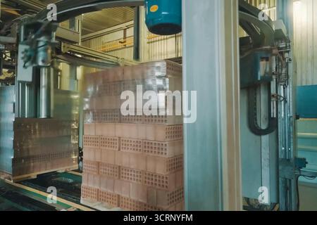 Wrapping a transport film of a brick pallet. Brick production, hollow ceramic bricks factory. Brick production, bricks factory. Stock Photo