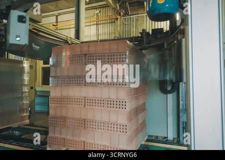Wrapping a transport film of a brick pallet. Brick production, hollow ceramic bricks factory. Brick production, bricks factory. Stock Photo