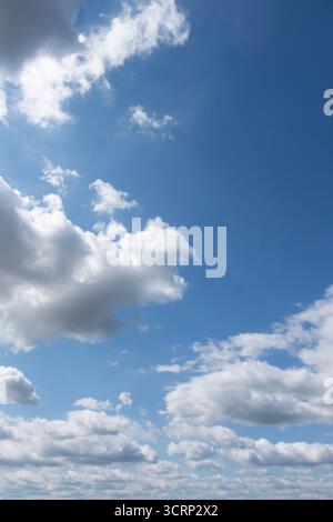 Blue sky with scattered white clouds on a bright sunny day, clear atmosphere background Stock Photo