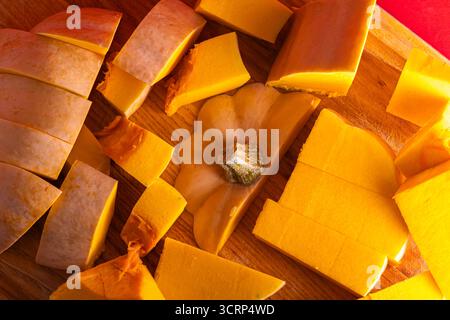 Fresh butternut pumpkin cut into pieces on a wooden cutting board. Concept of seasonal cooking, healthy vegetarian meals, vegan food preparation, orga Stock Photo